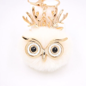 Détail du porte-clés hibou en peluche avec bois dorés et texture en fausse fourrure