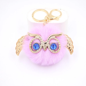 Détail d'un porte-clés hibou en peluche rose avec ailes dorées et yeux perlés