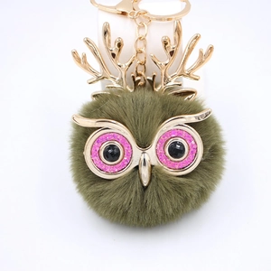 Gros plan du porte-clés hibou en peluche verte avec bois dorés et yeux à paillettes roses