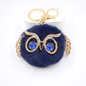 Gros plan du porte-clés hibou bleu duveteux avec ailes dorées et yeux brillants