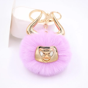 Detail of pink faux fur bull keychain with gold metal horns and lobster clasp on white