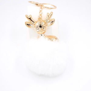 Détail d'un porte-clés tête de cerf dorée avec pompon en fourrure blanche et chaîne