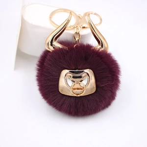 Close-up of plush bull keychain with purple pompom and golden bull horns design