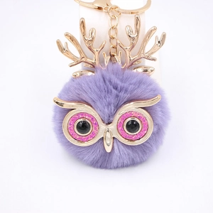 Détail du porte-clés hibou en peluche violette avec bois dorés et yeux à paillettes