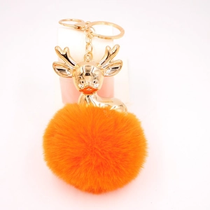 Détail du pendentif renne en métal doré brillant avec pompon orange duveteux