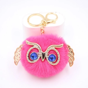 Gros plan du porte-clés hibou rose moelleux avec yeux en pierres bleues et ailes dorées