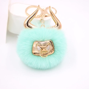 Close-up of mint green faux fur pompom keychain with golden bull horns and ring