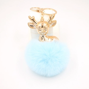 Détail d'un porte-clés renne doré avec pompon bleu clair et fermoir métallique