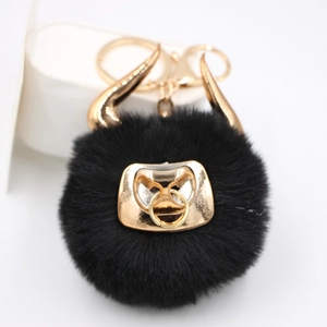 Detail of black faux fur bull keychain with gold horns and metallic hardware for bags