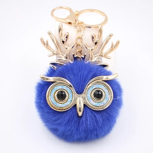 Détail du porte-clés chouette en peluche bleu roi avec bois dorés et yeux pailletés