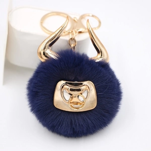 Detail of navy blue faux fur bull keychain with golden horns and metallic nose ring