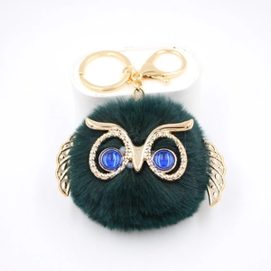Détail du porte-clés hibou avec fausse fourrure vert foncé et éléments dorés
