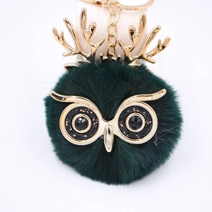 Détail du porte-clés hibou avec boule de fourrure vert foncé et bois de renne dorés
