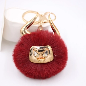 Detail of red faux fur bull plush keychain with golden horns and nose ring accent