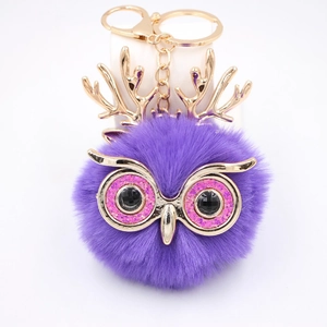 Vue détaillée du porte-clés hibou en peluche violet avec bois dorés et yeux en paillettes