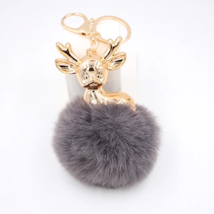 Détail d'un porte-clés cerf avec bois dorés et pompon en fausse fourrure gris foncé