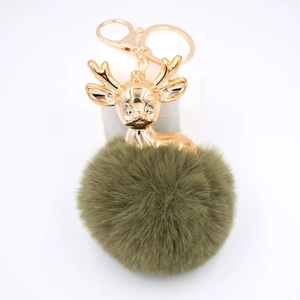 Vue détaillée du pompon en fausse fourrure vert olive et du porte-clés tête de cerf doré