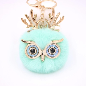 Détail du porte-clés hibou en peluche vert menthe avec bois dorés et fermoir mousqueton