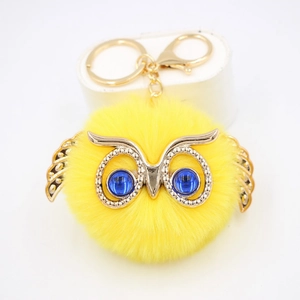 Porte-clés pompon chouette en fausse fourrure jaune avec ailes dorées et yeux bleus