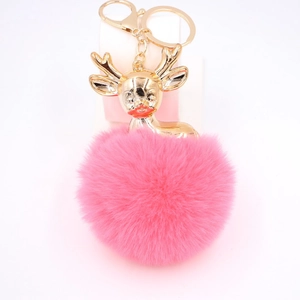 Gros plan du porte-clés pompon rose avec renne doré et fermoir mousqueton