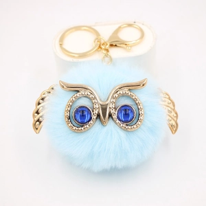 Détail d'un porte-clés hibou bleu clair en peluche avec finitions dorées et cristaux