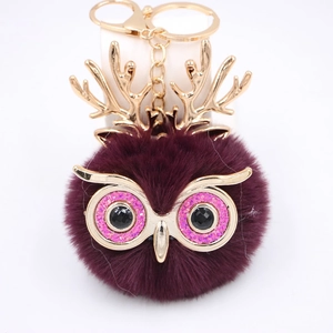 Détail du porte-clés hibou en fourrure bordeaux avec bois dorés et masque pailleté