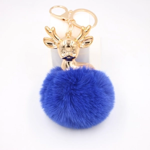 Détail du pendentif tête de cerf doré et du grand pompon en fausse fourrure bleu marine