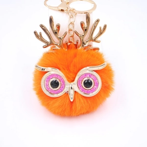 Détail macro du porte-clés hibou en fausse fourrure orange avec bois dorés et paillettes