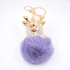 Détail d'un pendentif tête de cerf doré avec porte-clés pompon en fausse fourrure violette