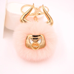 Detail view of pink plush bull keychain with golden horns and metallic nose ring detail