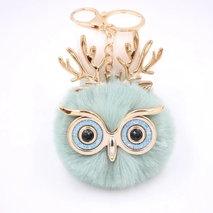 Détail du porte-clés hibou pompon vert clair avec bois dorés et fermoir métallique