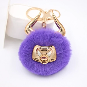 Detailed close-up of a purple faux fur bull pompom keychain with golden metal horns