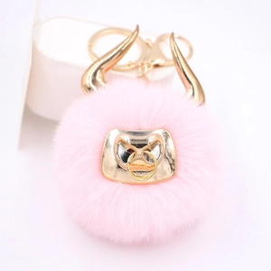 Close-up of pink faux fur bull keychain with golden horns and metallic lobster clasp