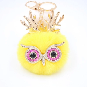 Détail du porte-clés hibou en peluche jaune avec bois dorés et yeux à paillettes