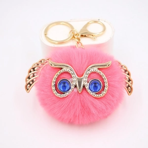 Détail d'un porte-clés hibou rose moelleux avec cadre doré et yeux en pierre bleue