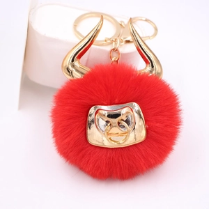 Detail of red faux fur pompom keychain with golden bull head ornament and lobster clasp