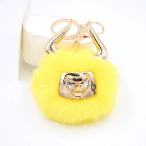 Detailed view of yellow bull faux fur pompom keychain with golden horns and hardware
