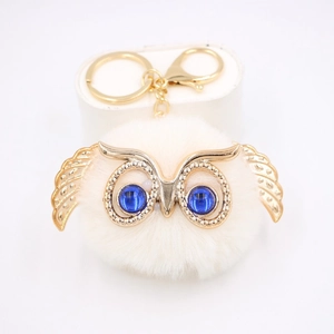 Vue détaillée du porte-clés chouette blanche en peluche avec ailes dorées et yeux bleus