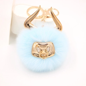Detail of light blue faux fur bull keychain with golden horns and metal nose ring clasp