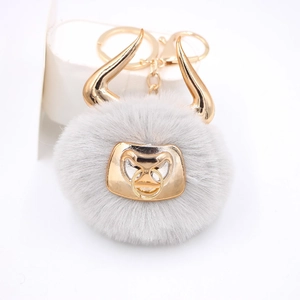 Detail of grey plush bull keychain with gold horns and metal nose ring clasp
