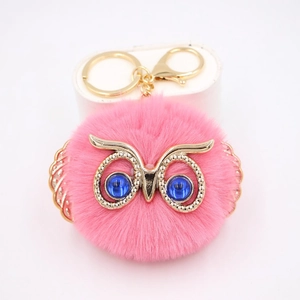 Détail du porte-clés hibou en fausse fourrure rose avec ailes dorées et yeux gemmes