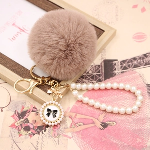 Close-up of faux rabbit fur pompom keychain with pearl strap and bow number 5 pendant
