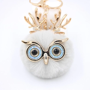 Détail du porte-clés hibou en fausse fourrure grise avec yeux bleus et bois dorés chic