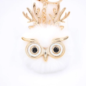 Détail du porte-clés chouette en peluche blanche avec bois dorés et accents cristallins