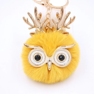 Détail du porte-clés hibou en peluche jaune avec bois dorés et pendentif décoratif