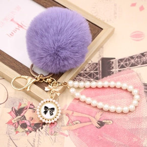 Purple faux rabbit fur pom pom keychain with white pearl wristlet and bow charm