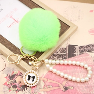 Detail of lime green faux rabbit fur keychain with pearl strap and bow pendant décor
