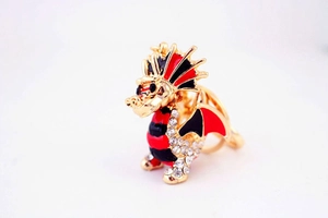 Détail d'un porte-clés dragon doré orné de strass brillants et d'émail rouge vif