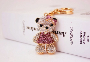 Detailed macro view of crystal bear keychain with pink rhinestone dress and gold hardware