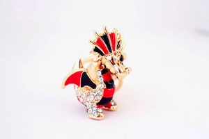 Détail macro d'une bague dragon dorée avec émail rouge et strass en cristal brillant